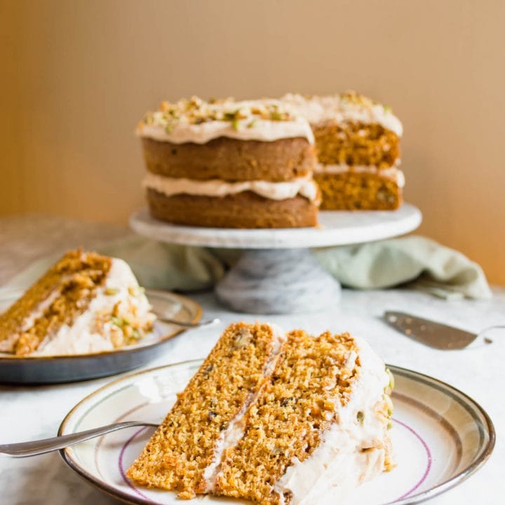 Slices of carrot cake on plates and cake in background.