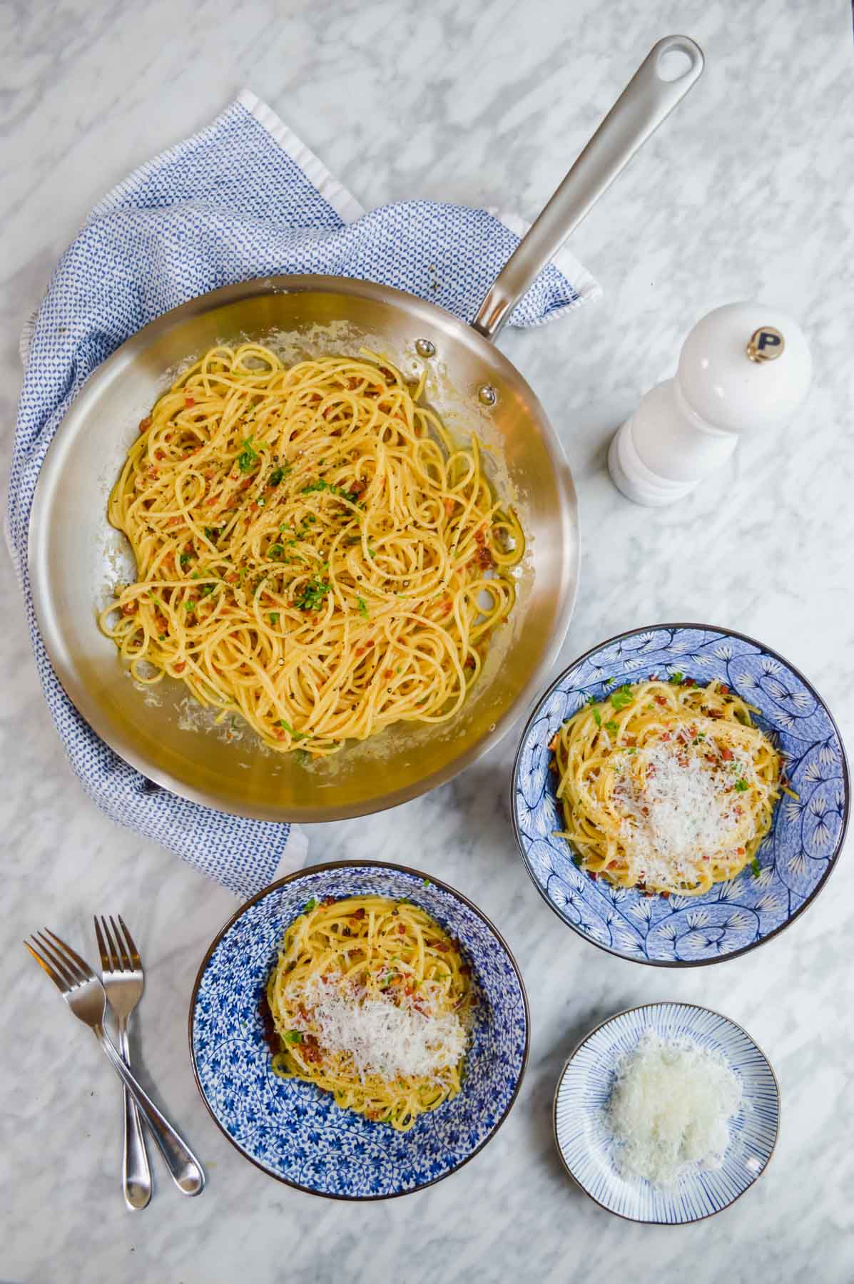 Spaghetti Carbonara in bowls and pan with parmesan cheese flatlay.