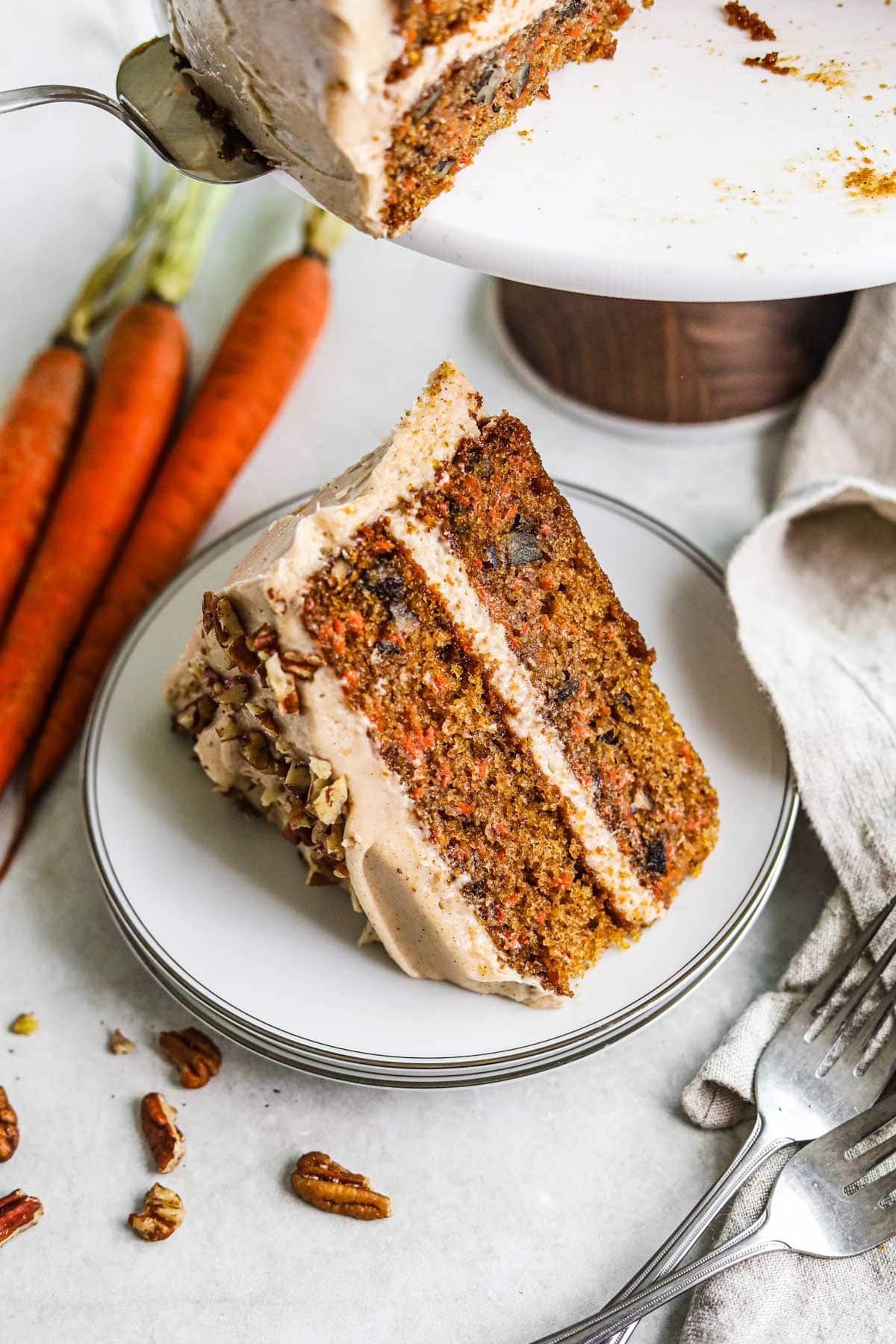 Moist and tender layered carrot cake with pecans and chai spiced cream cheese frosting on a plate.