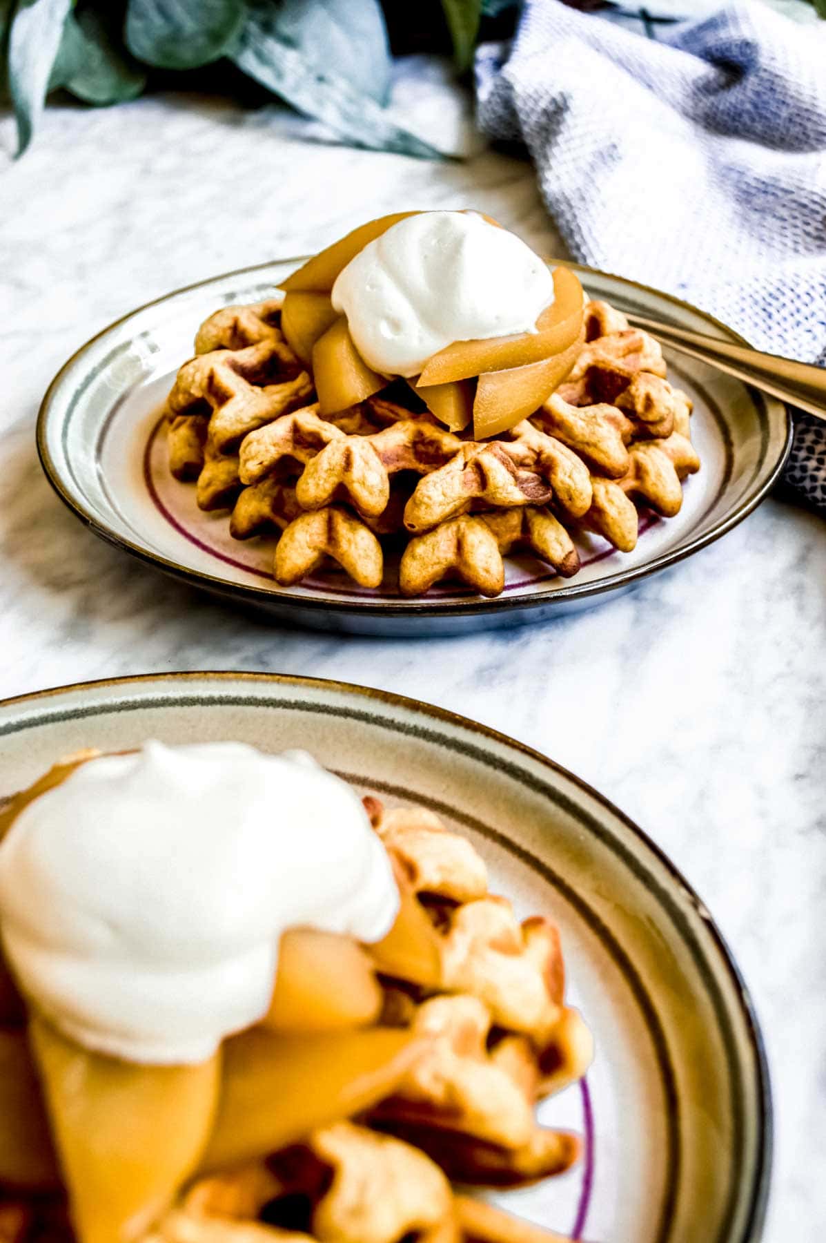 Belgian Waffles with Cinnamon Poached Pears on plates with whipped cream.