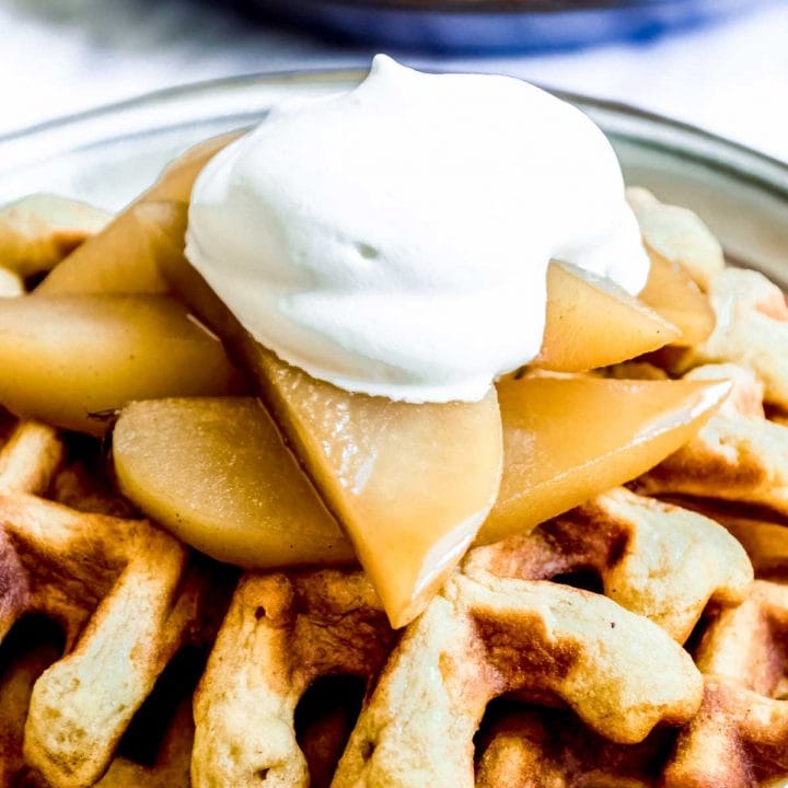 Belgian Waffles with Cinnamon Poached Pears on plate with whipped cream.