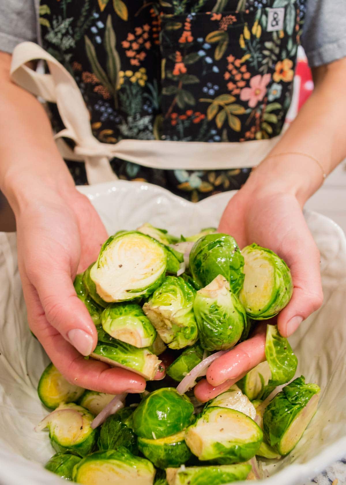 Hands in Maple Brussel Sprouts with seasoning.