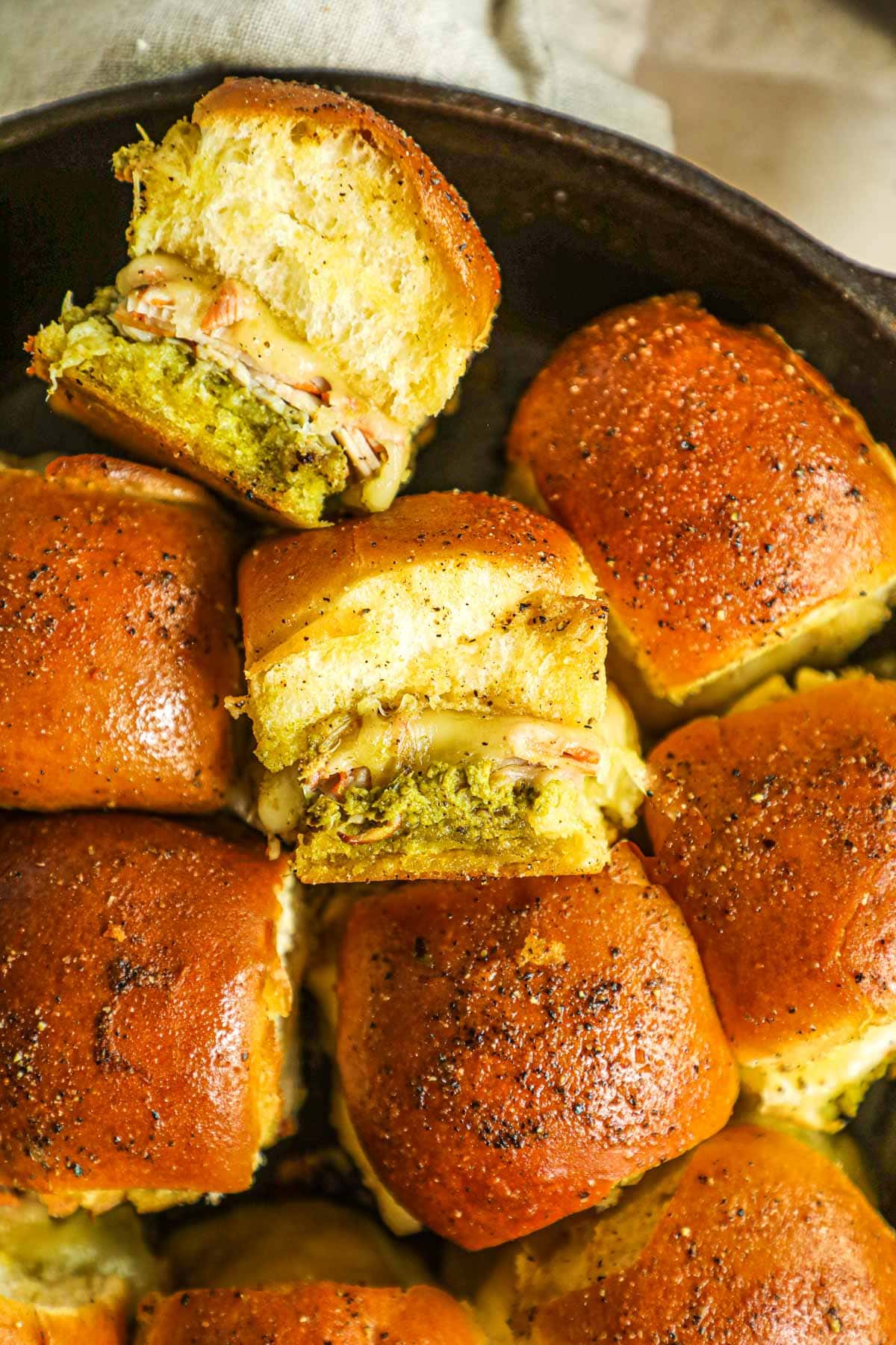 Hawaiian roll turkey pesto sliders with Swiss cheese and honey in a cast iron skillet.