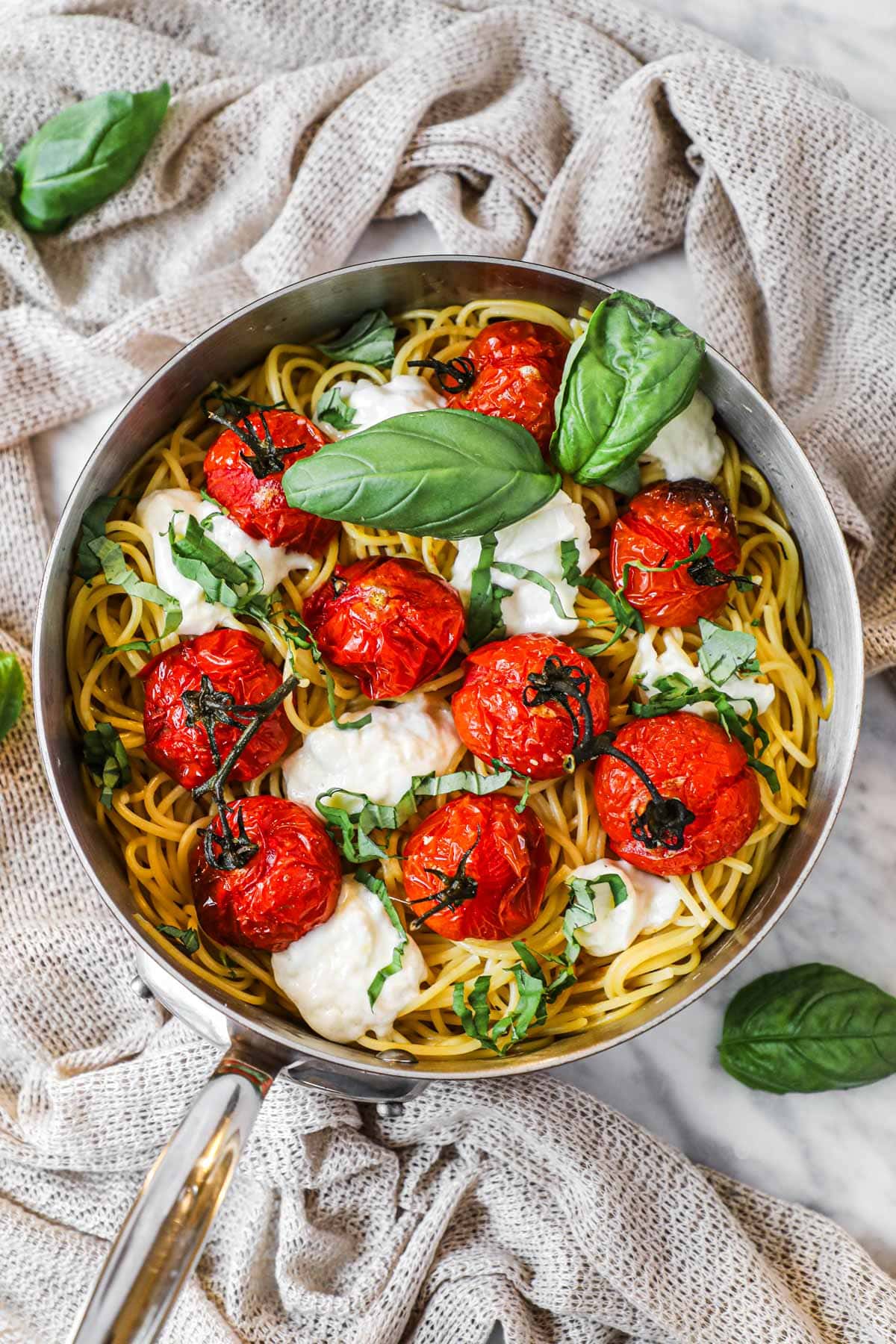 Roasted tomato pasta with globs of torn burrata cheese and fresh basil in a copper Mauviel pan.