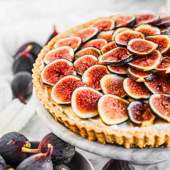 Fig tart with whipped mascarpone and honey filling on a marble serving platter.