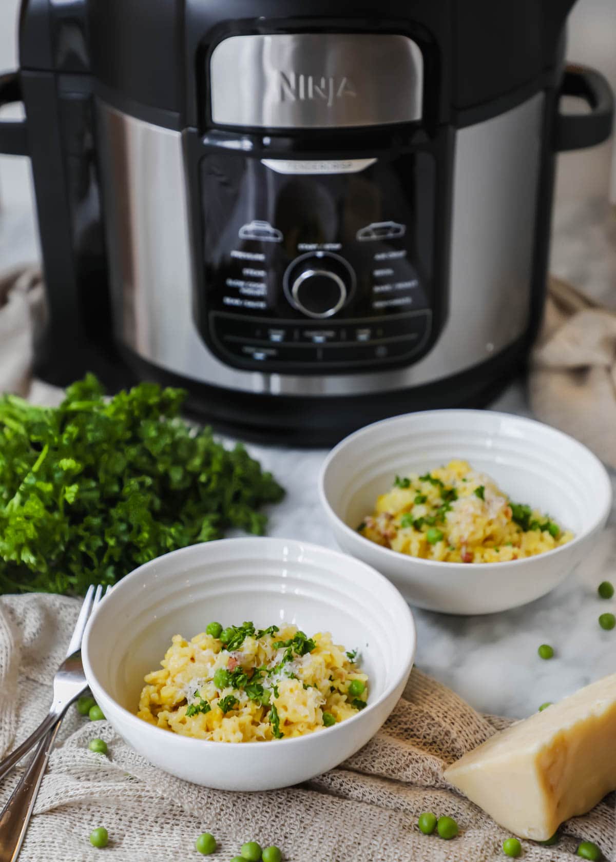 Instant Pot Risotto with Pancetta and Peas in bowls in front of Ninja Foodi instant pot.