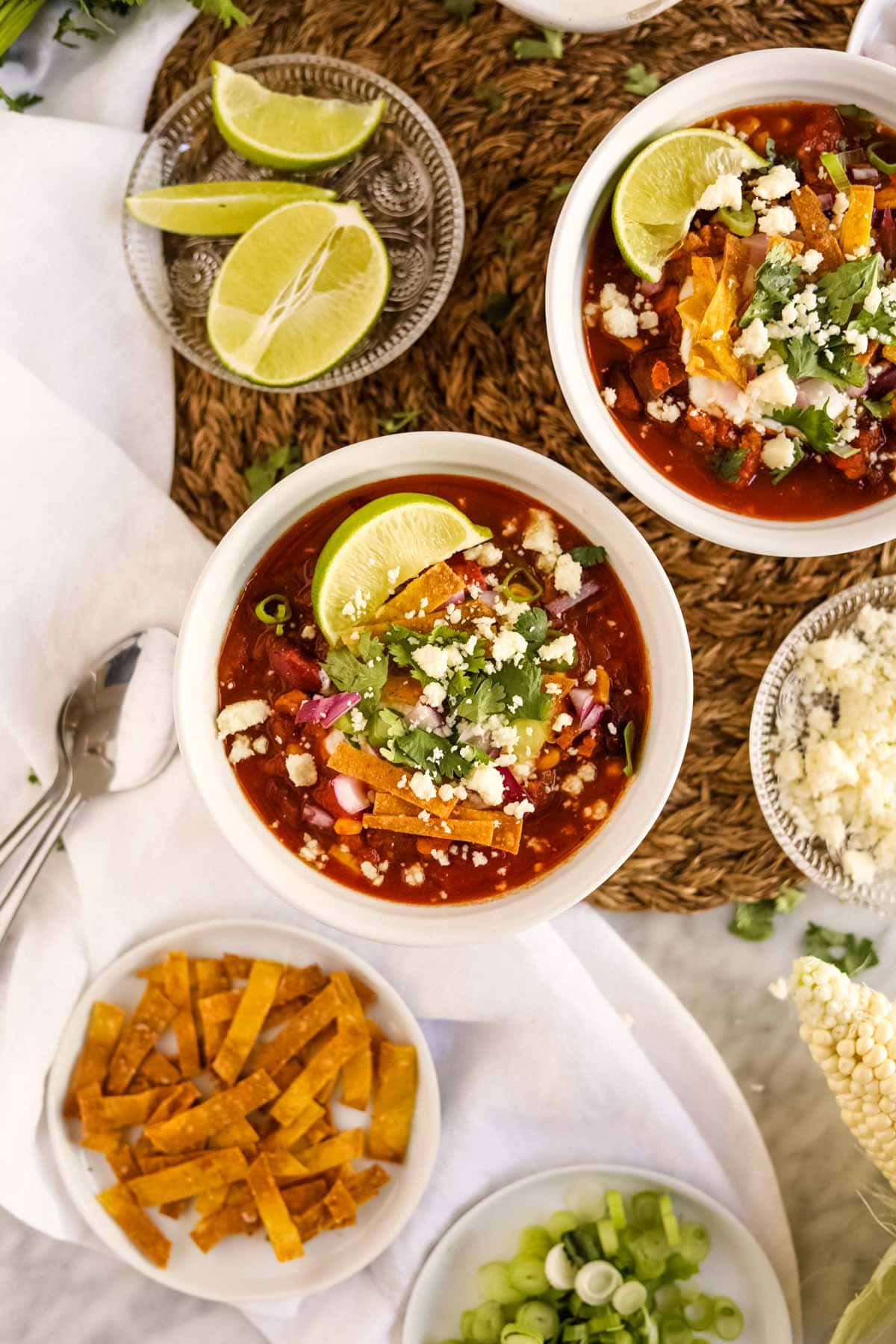 Healthy Turkey Chili in bowls with toppings and with corn, bell pepper, and green chiles flatlay.