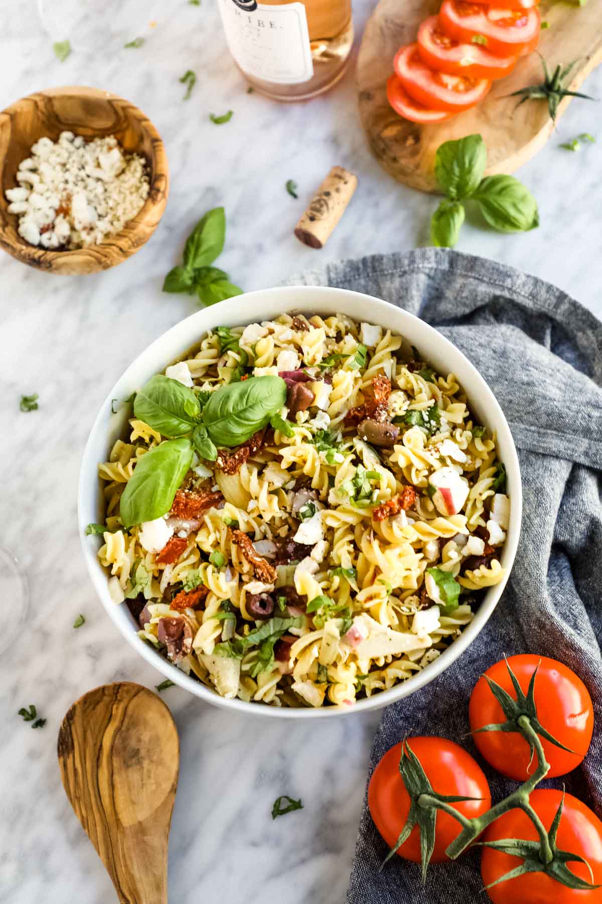 Pasta salad with Italian ingredients in bowl flatlay.