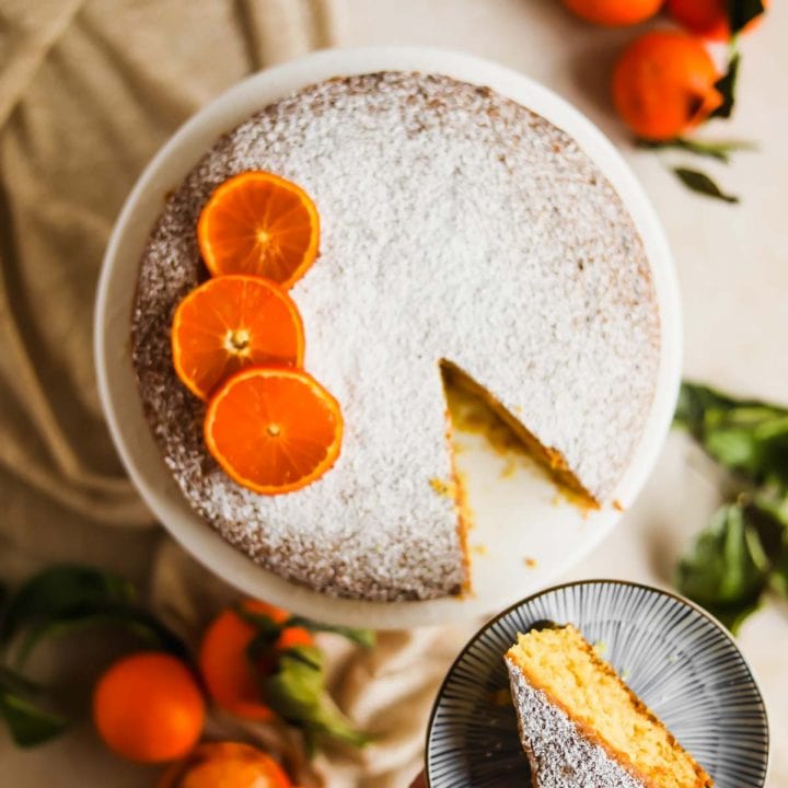 Clementine Olive Oil Cake with sliced citrus and cake server flatlay.
