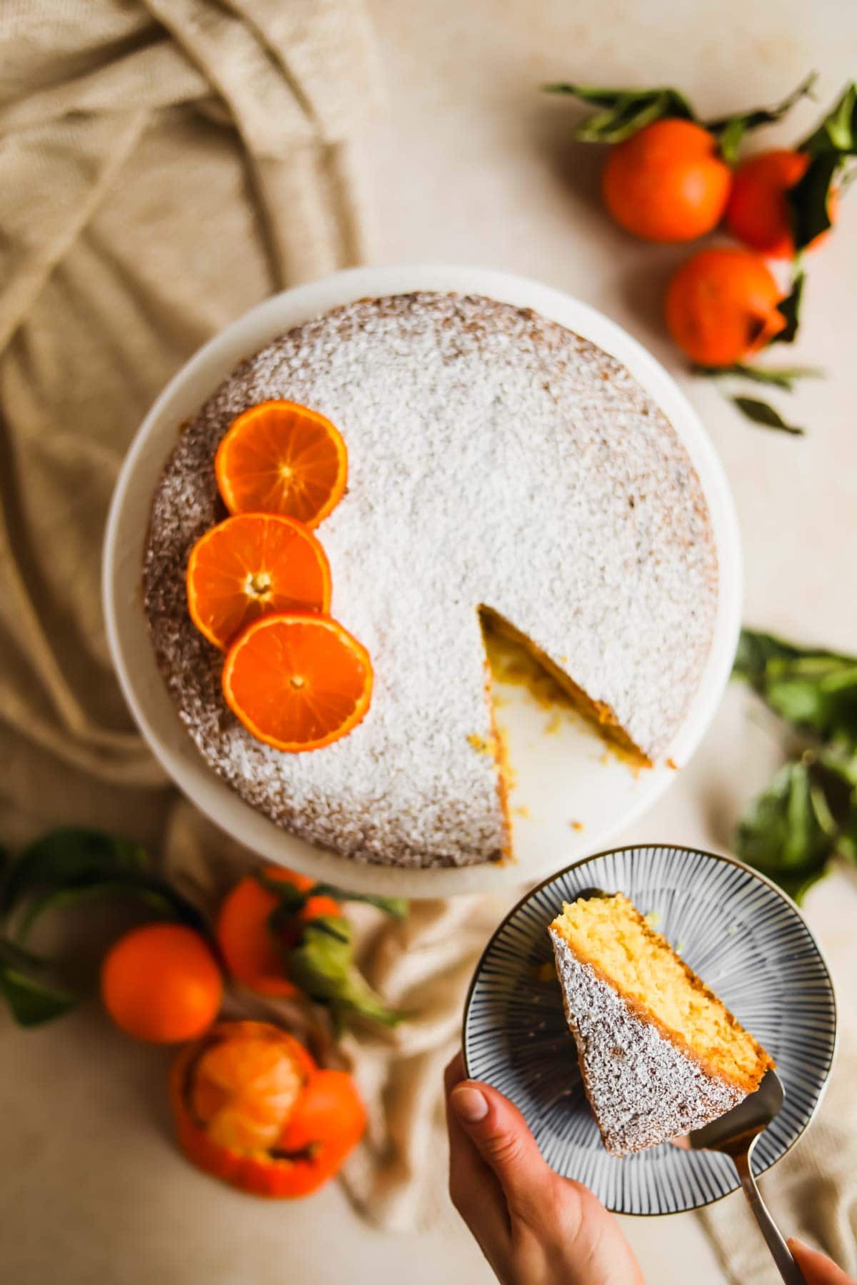 Clementine Olive Oil Cake with sliced citrus and cake server flatlay.