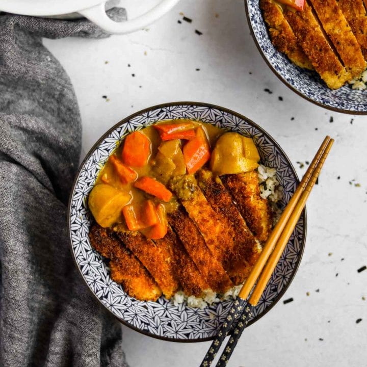Chicken Katsu Curry in blue Japanese bowl with chopsticks and dutch oven in an overhead shot