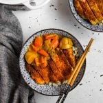 Chicken Katsu Curry in a blue Japanese porcelain bowl with blue and wood bamboo chopsticks and a white Le Creuset dutch oven