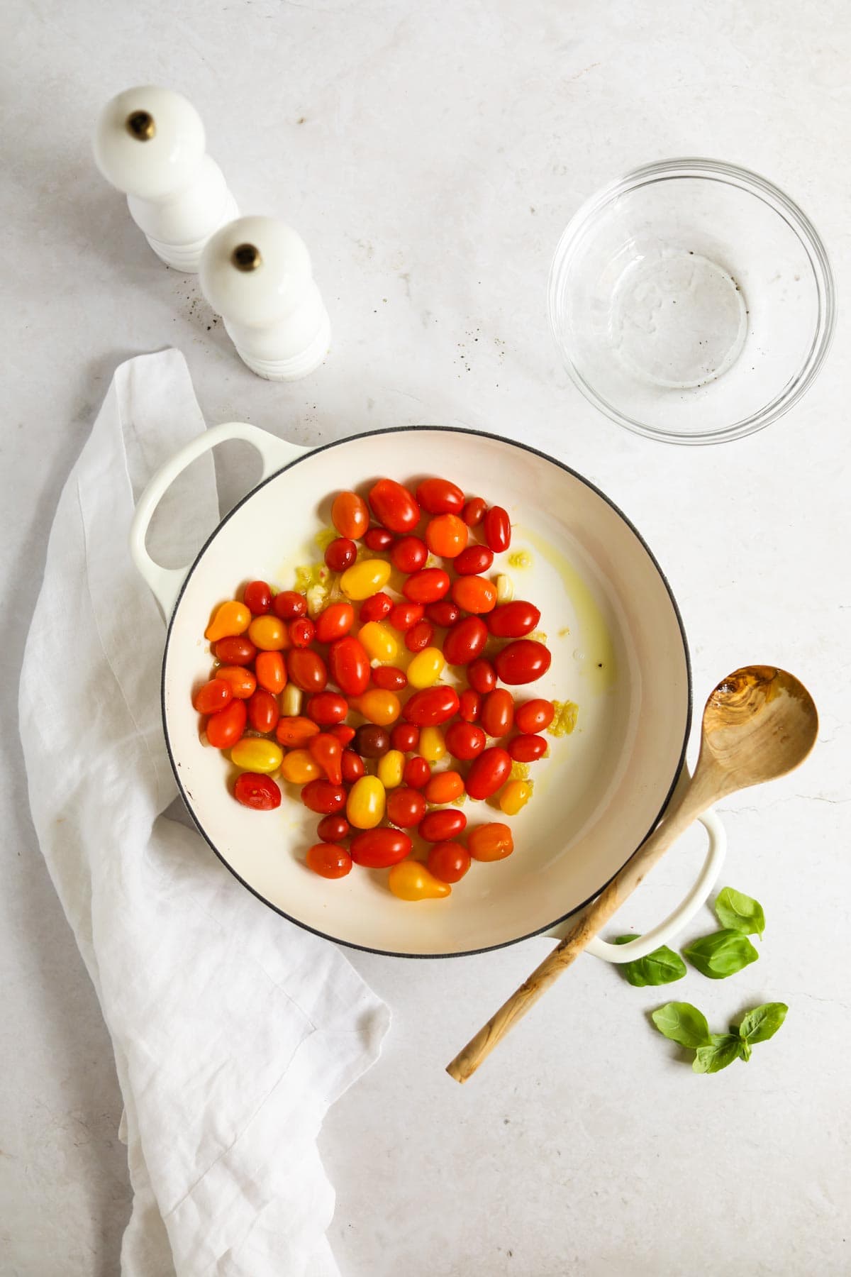 cherry tomatoes cooking in a white Le Creuset braiser