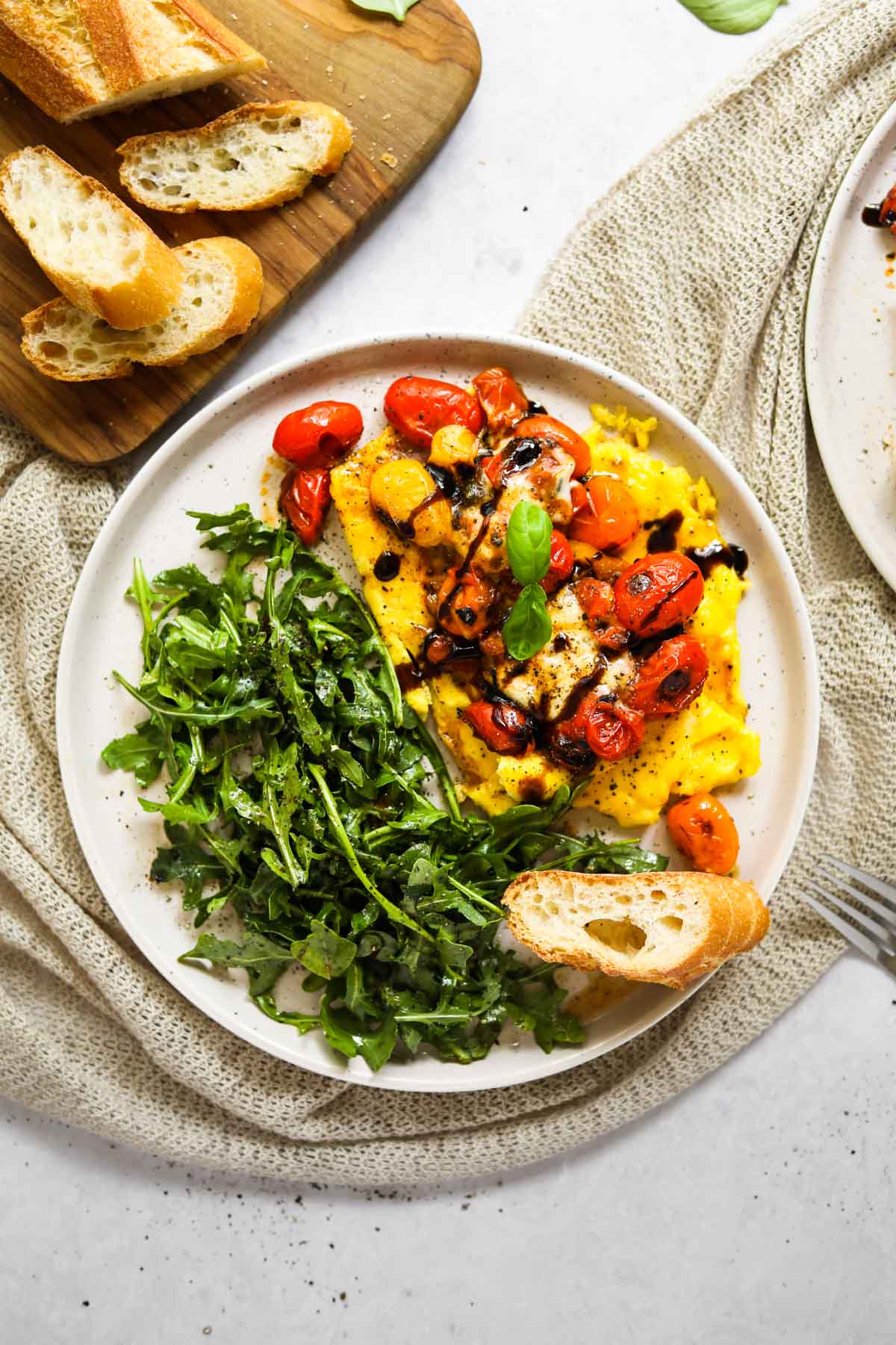 Soft-scrambled eggs with burrata, blistered tomatoes, arugula and a toasted baguette