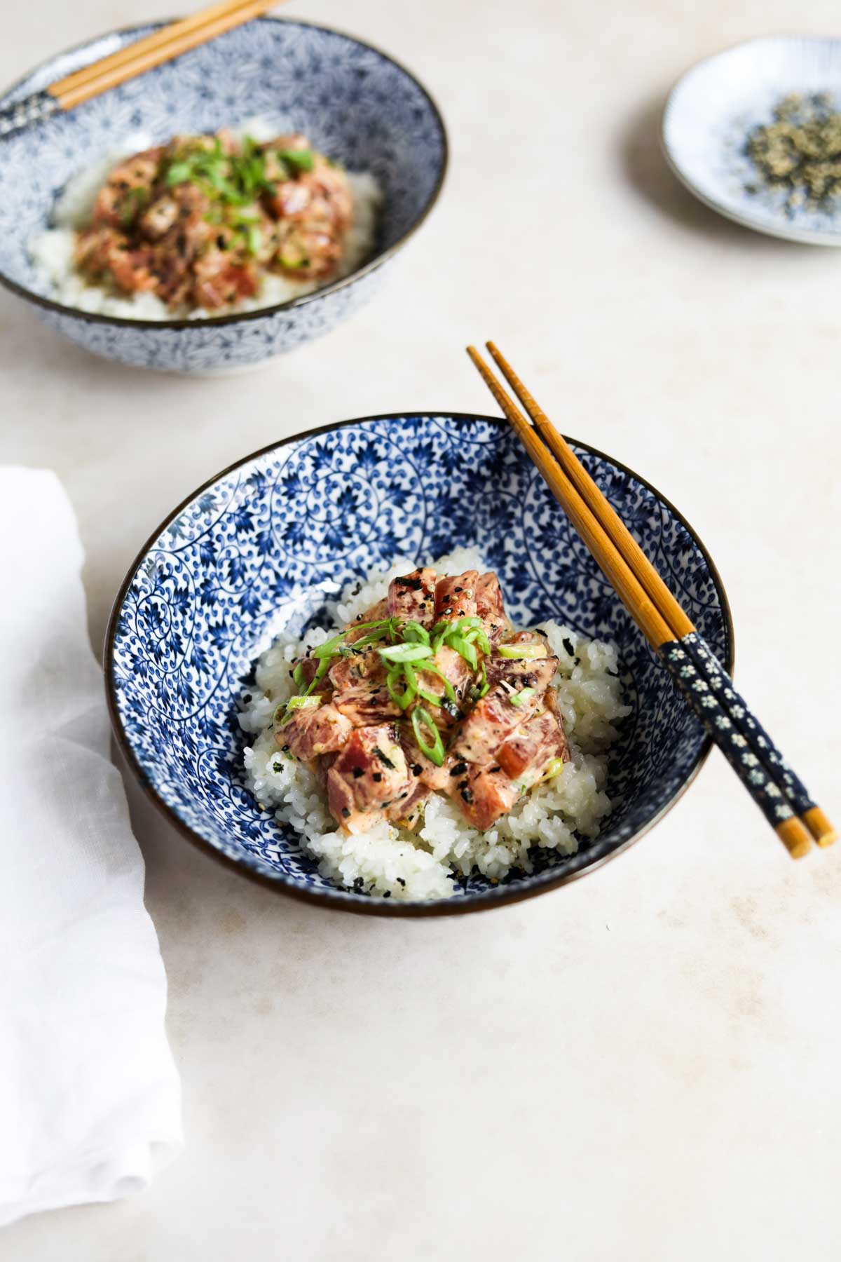 Spicy ahi tuna poke bowl with chopsticks in a blue Japanese bowl.