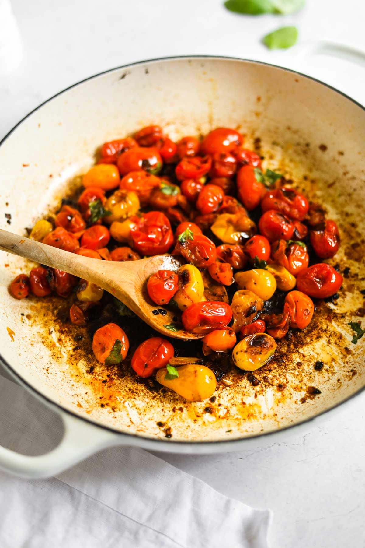 Blistered Cherry Tomatoes with olive wood spoon and Le Creuset White Braiser.