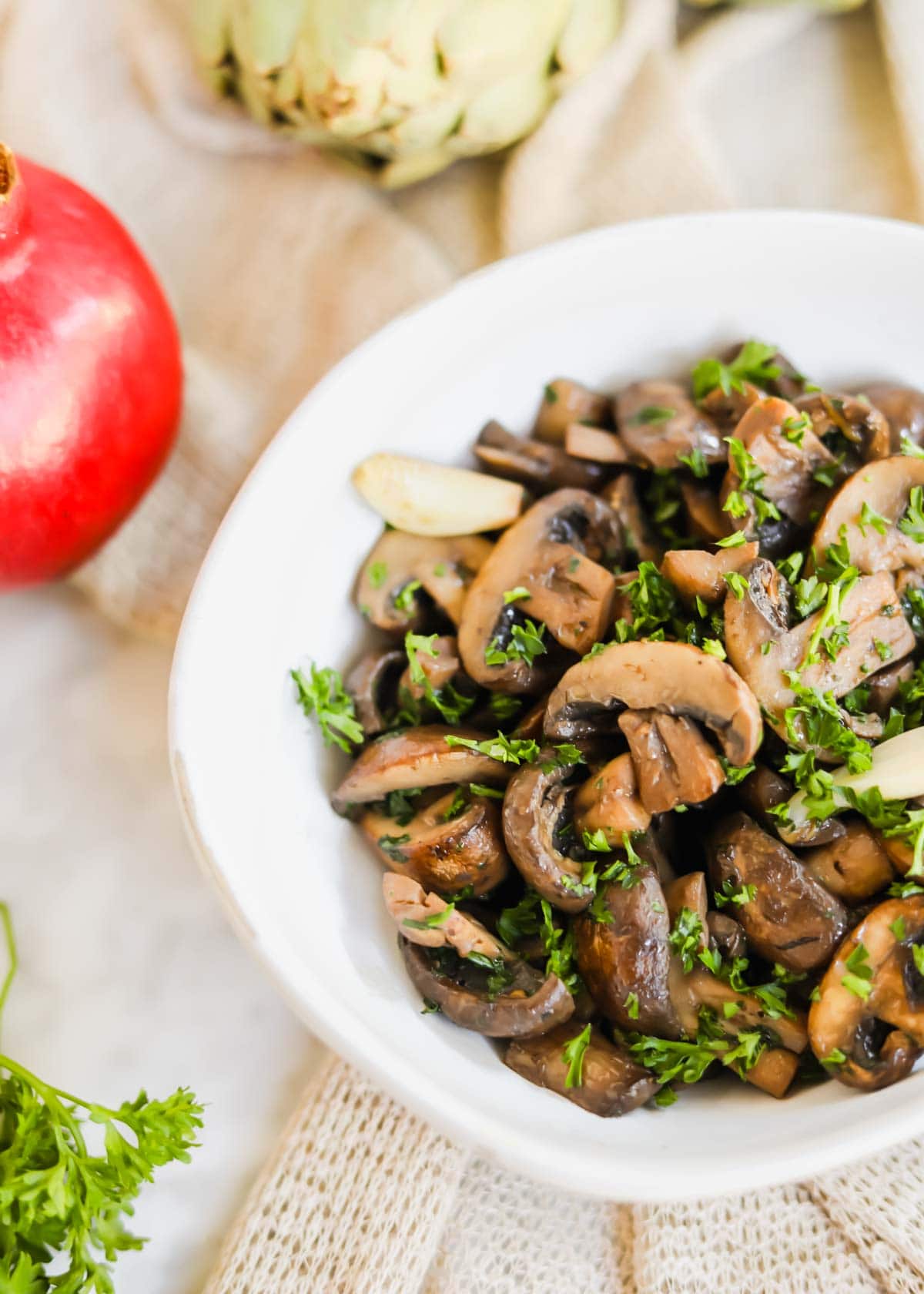 Sautéed mushrooms with White Wine in white bowl with parsley, garlic, and seasoning.