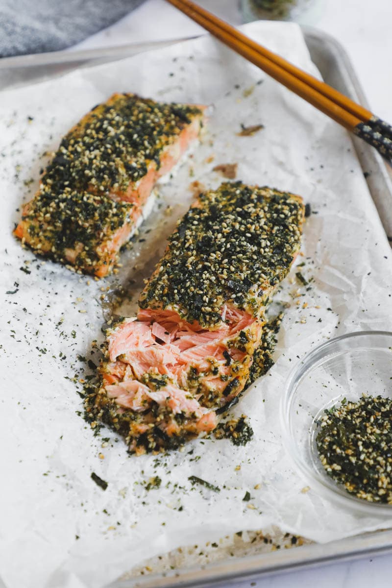 Baked salmon filet on a baking sheet with sprinkled furikake on top.