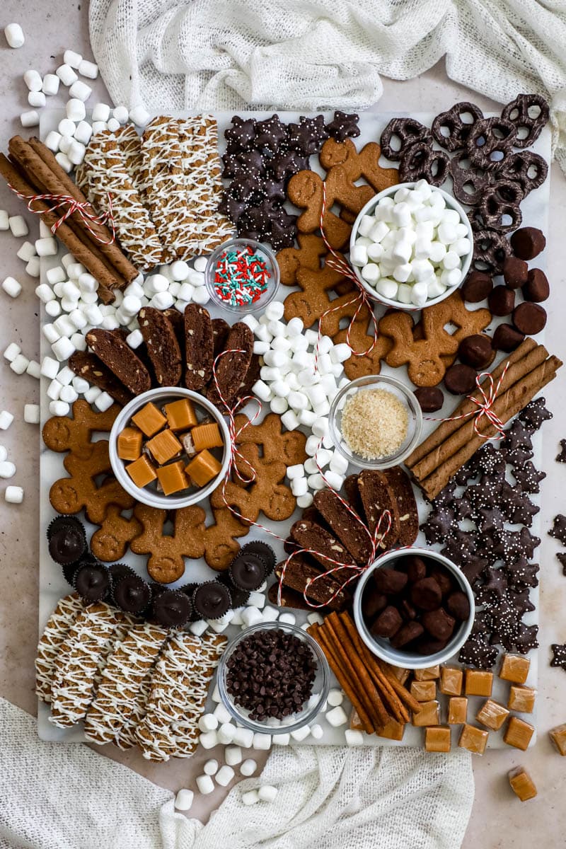 Hot chocolate/ hot cocoa board with cookies, chocolates, marshmallows, and caramels.