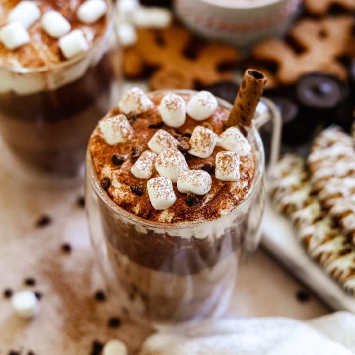 Oat milk hot chocolate with vegan whipped cream, vegan marshmallows, cocoa powder, and a pirouette creme wafer cookie.
