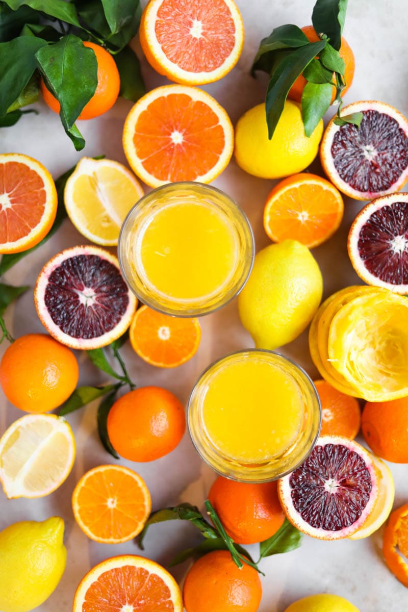 Flatlay orange juice in glasses and sliced oranges.
