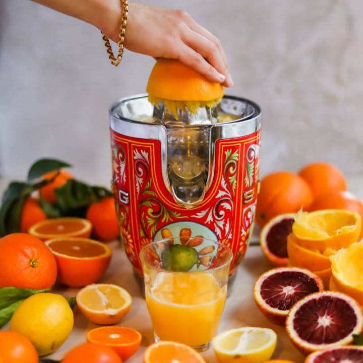 Oranges being juiced with a red Dolce and Gabbana Smeg juicer.