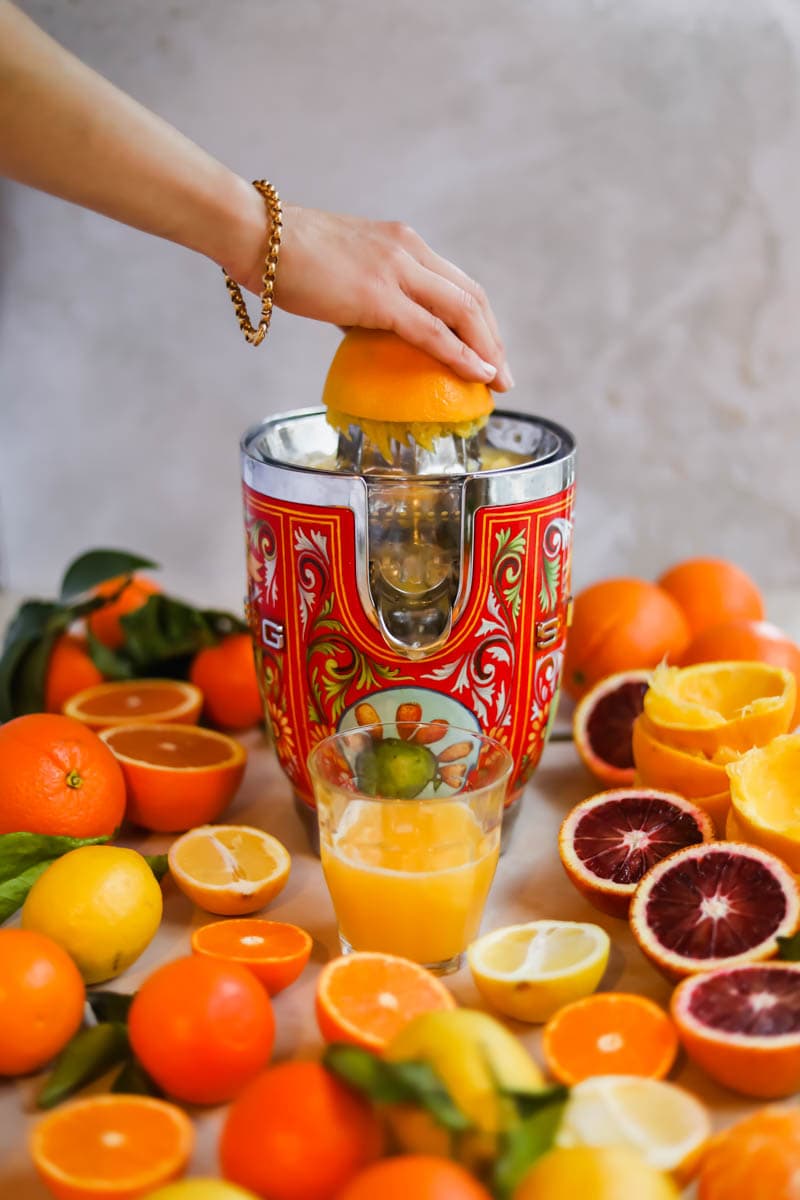 Oranges being juiced with a red Dolce and Gabbana Smeg juicer.