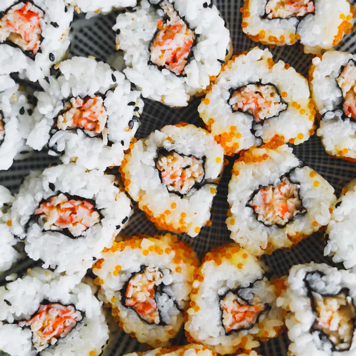 Closeup shot of spicy kani rolls with imitation crab, tobiko, rice, and sesame seeds.