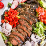 Flank steak salad with lettuce, radish, tomato, bell pepper, shallot, green onion, and a balsamic dressing.