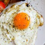 Closeup of a sunny side up egg with Maldon salt and pepper.