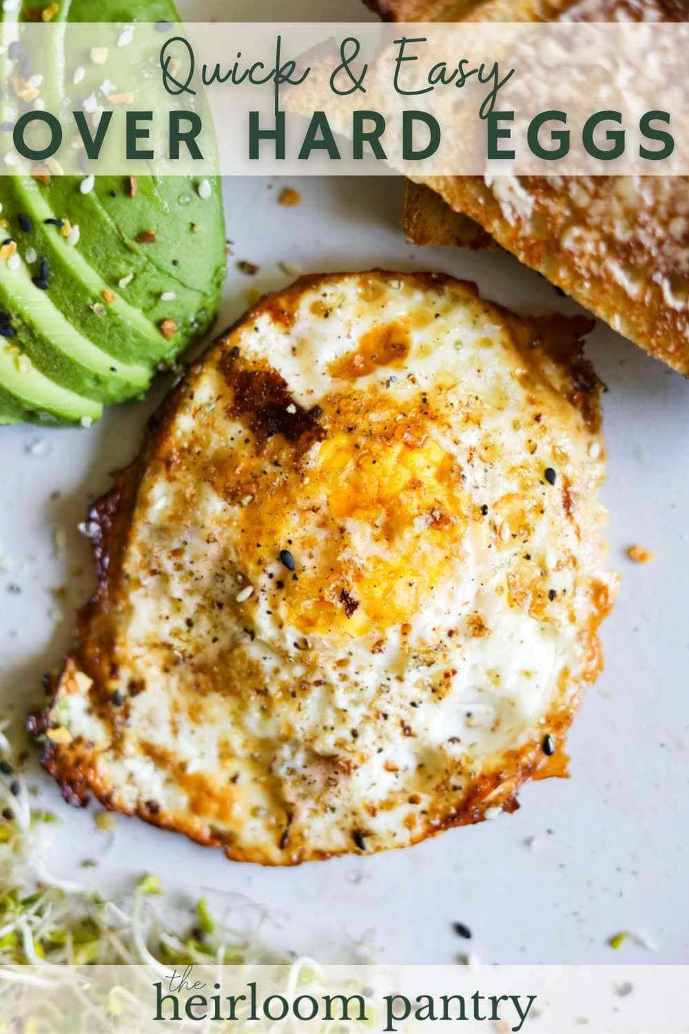 Over hard eggs with butter, salt, and pepper on a plate with avocado, toast, and sprouts.