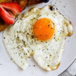 Closeup shot of a fried sunny side up egg on a plate.