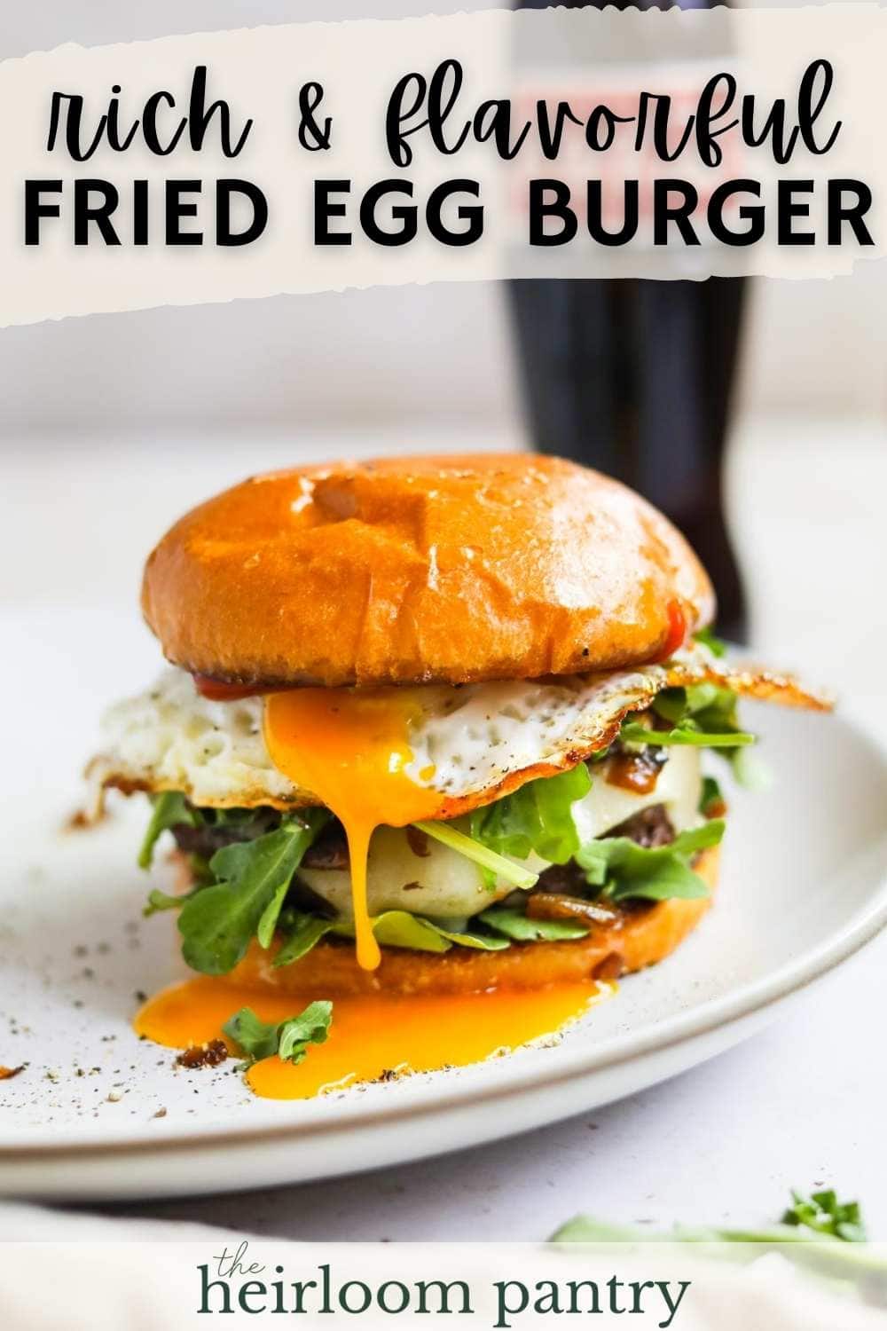 Pinterest pin of fried egg cheeseburger with yolky egg, arugula, and grilled onions on a plate.