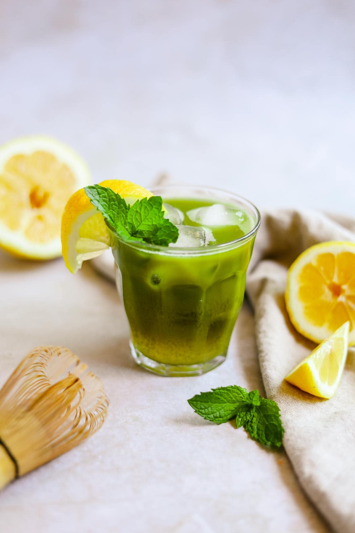 Matcha green tea lemonade in a glass with ice, lemon, and mint.