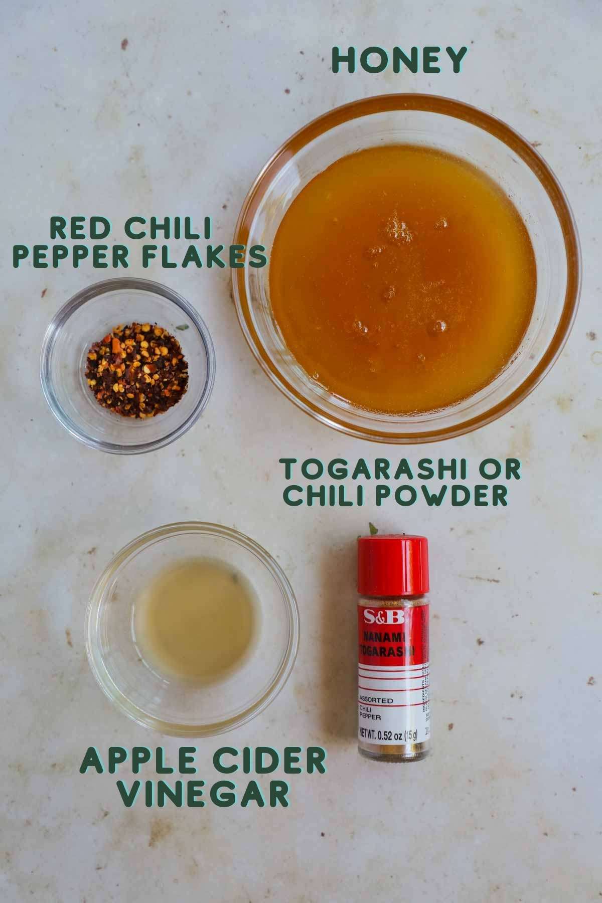 Ingredients for hot honey sauce, including honey, red chili pepper flakes, apple cider vinegar, and togarashi or chili powder.