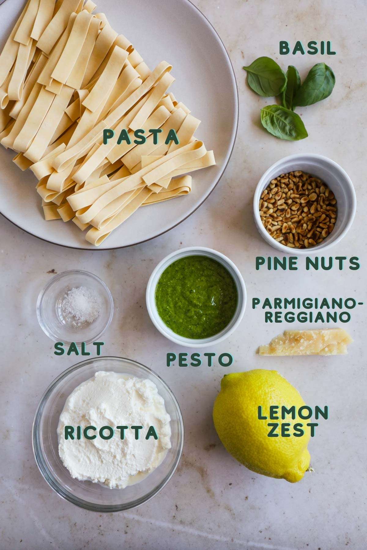 Ingredients to make creamy pesto pasta, including pasta, salt, pesto, pine nuts, basil, ricotta, lemon zest, and Parmigiano-reggiano.