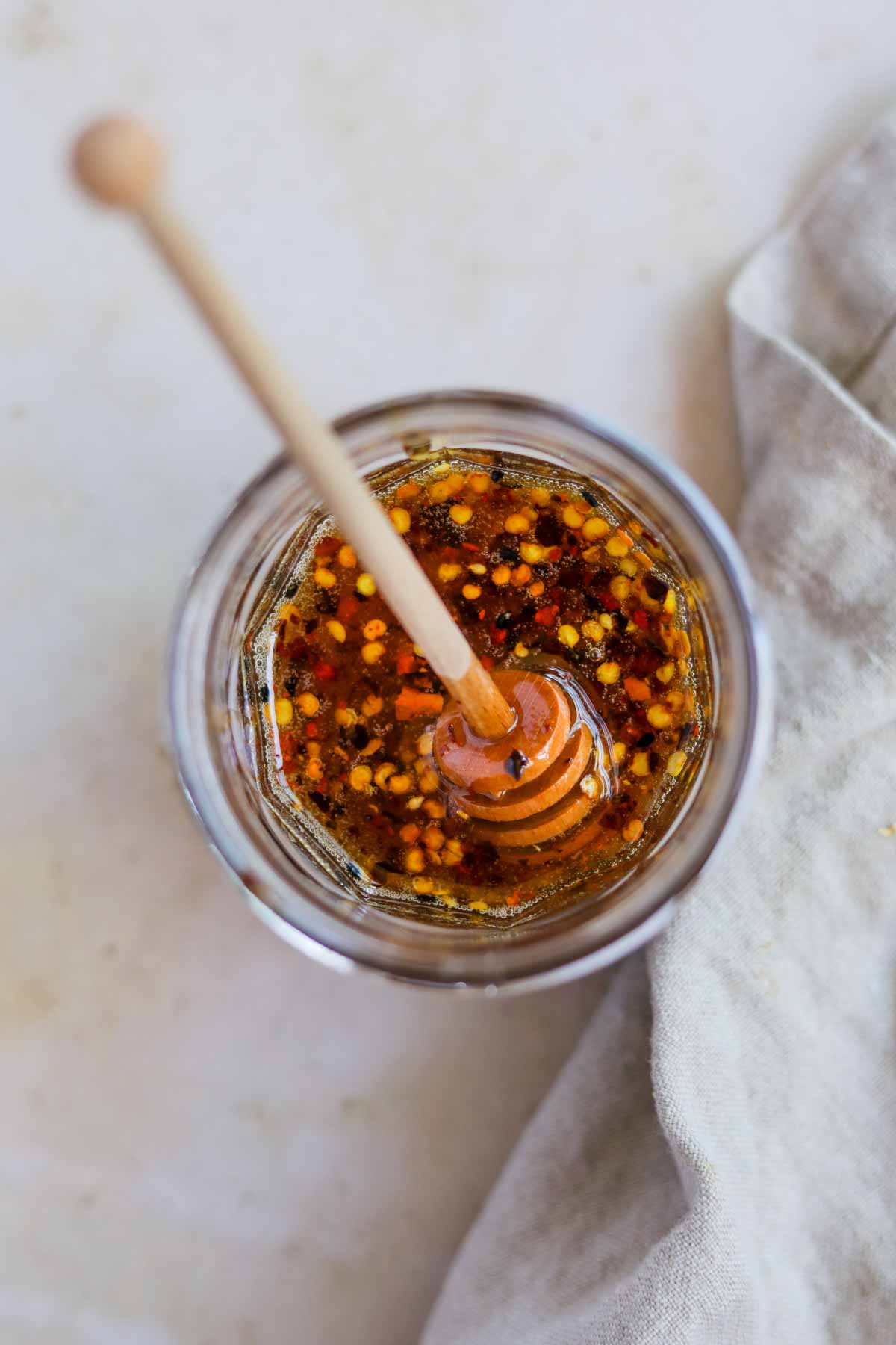 Spicy honey sauce in a jar with honey dripper.