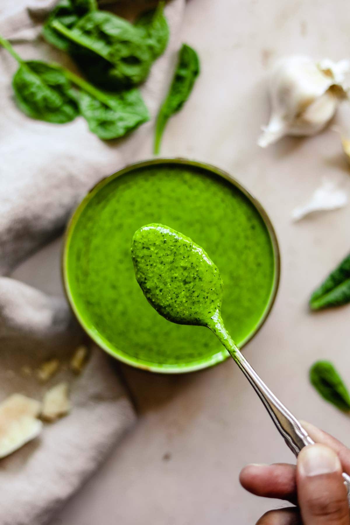 Bright green spinach pesto on a spoon.
