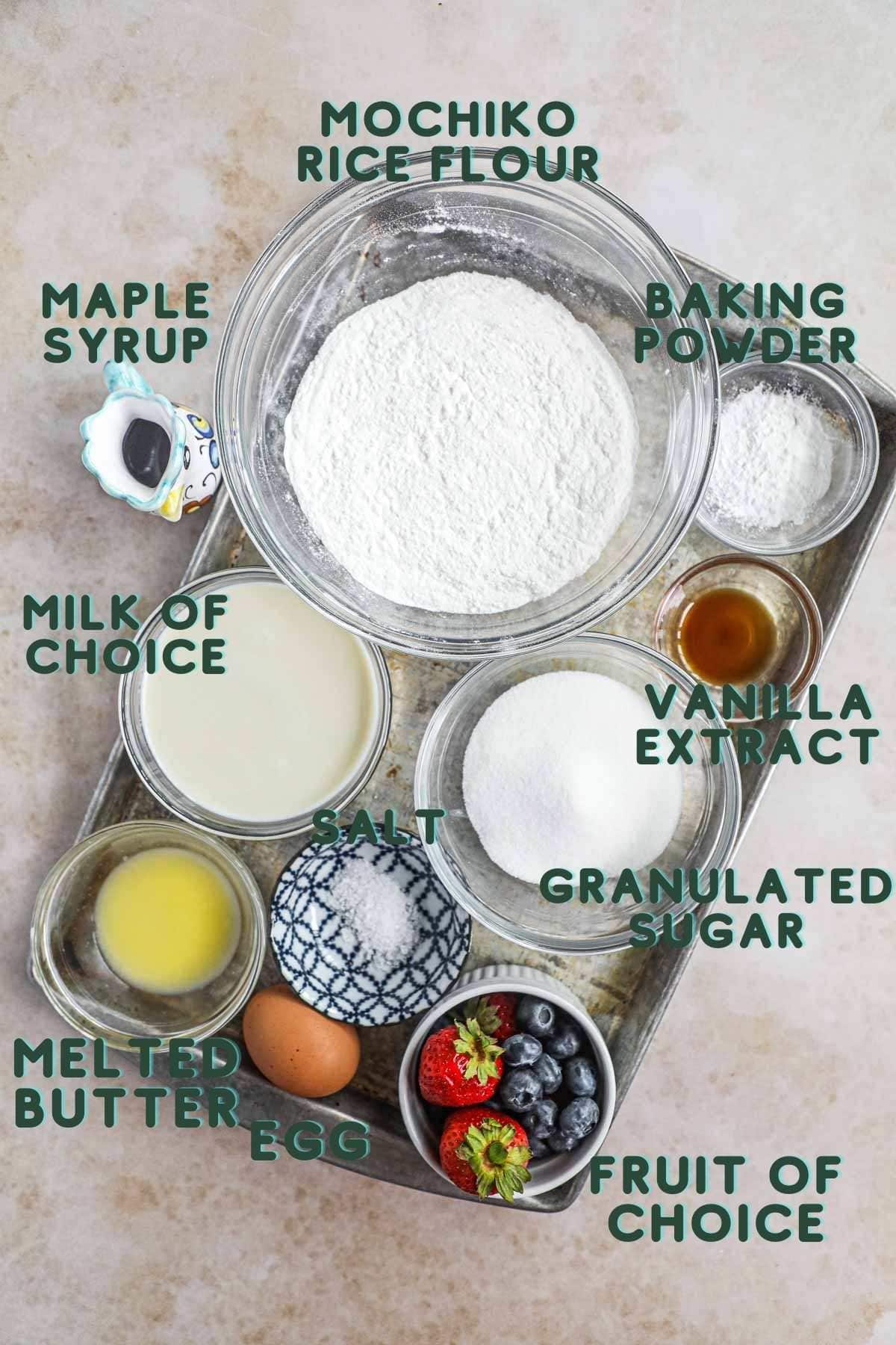 Ingredients to make easy, simple gluten-free mochi waffles, including mochiko rice four, milk, baking powder, vanilla extract, salt, granulated sugar, melted butter, egg, syrup, and fruit. 