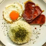 Rice with furikake, sunny side up eggs, and fried teriyaki spam on a plate.