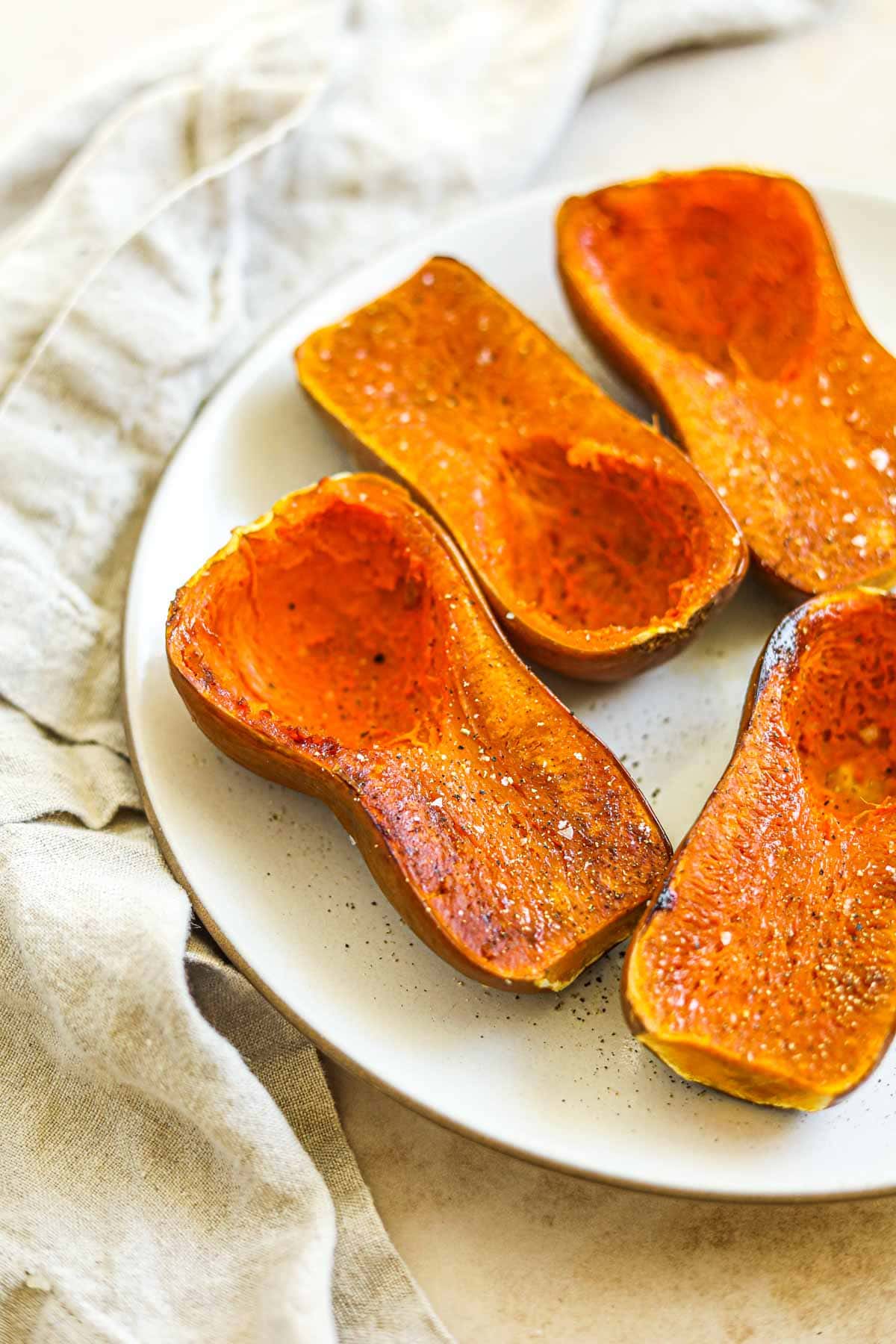 Roasted honeynut squash with salt and pepper arranged on a serving plate.