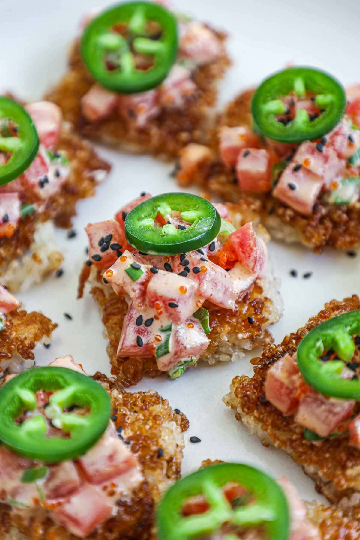 Spicy tuna with crispy rice topped with jalapeño on a platter.