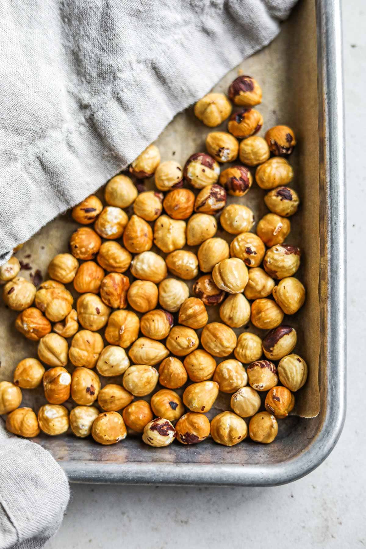 Flatlay view of roasted hazelnuts on a sheet pan.