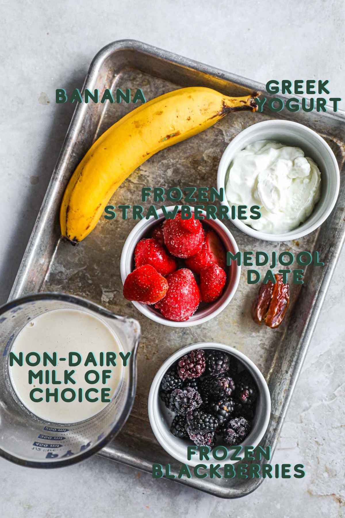 Ingredients to make blackberry strawberry and banana smoothie, including banana, frozen strawberries and blackberries, medjool date, Greek yogurt, and non-dairy milk of choice.