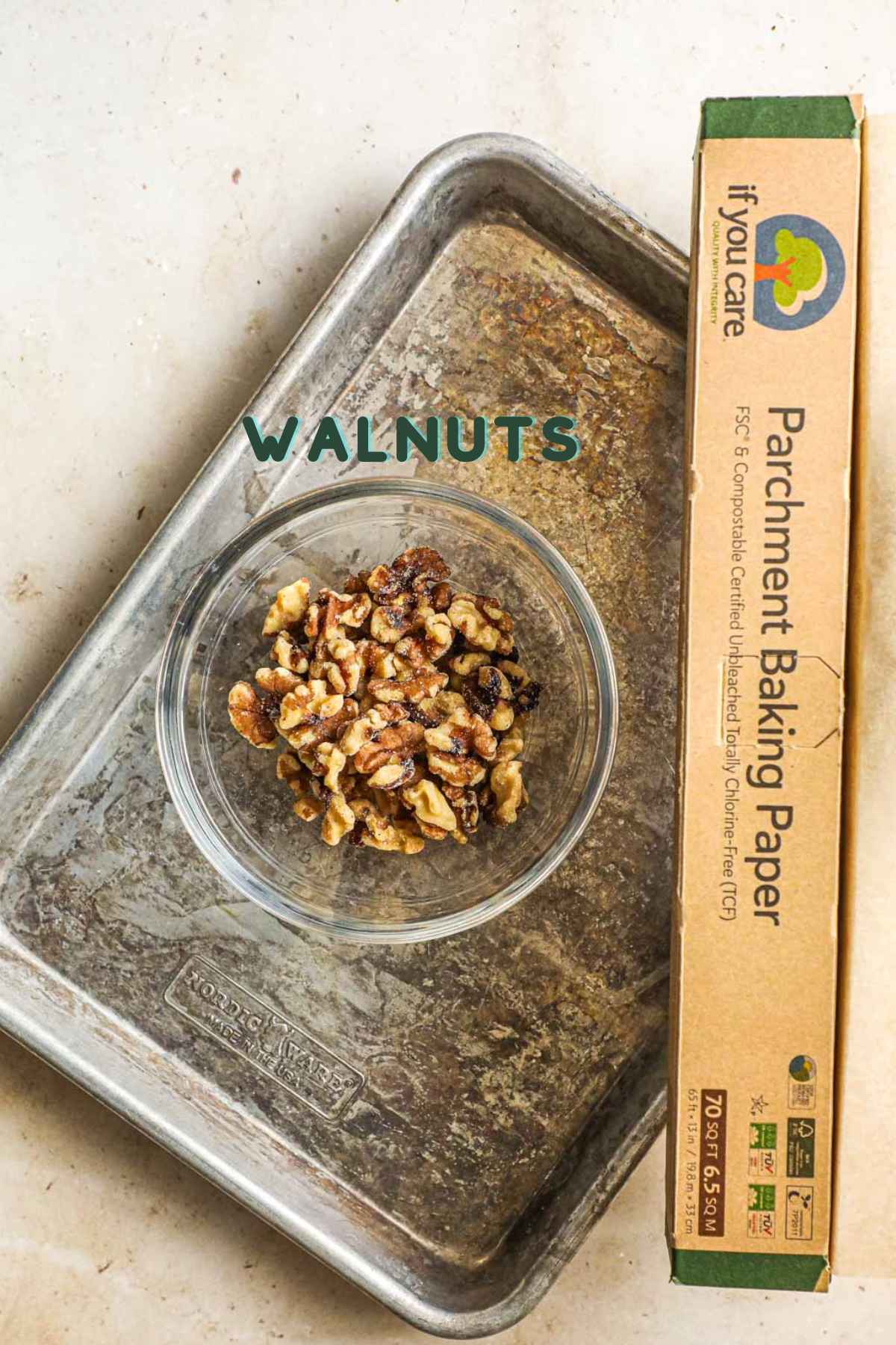 Ingredients to make roasted walnuts, including walnuts, parchment paper, and baking sheets.
