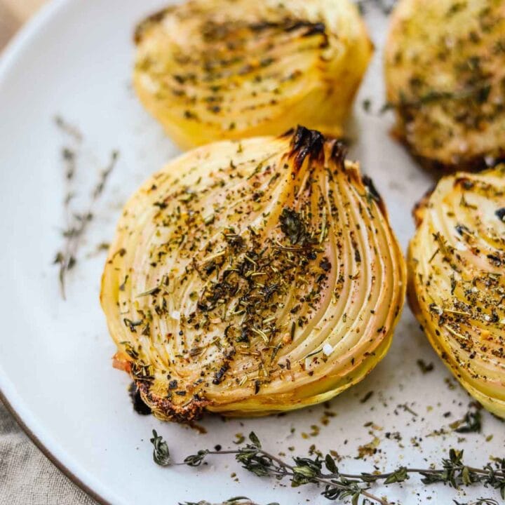 Oven roasted onions with herbs baked and served on a Heath Ceramics platter.
