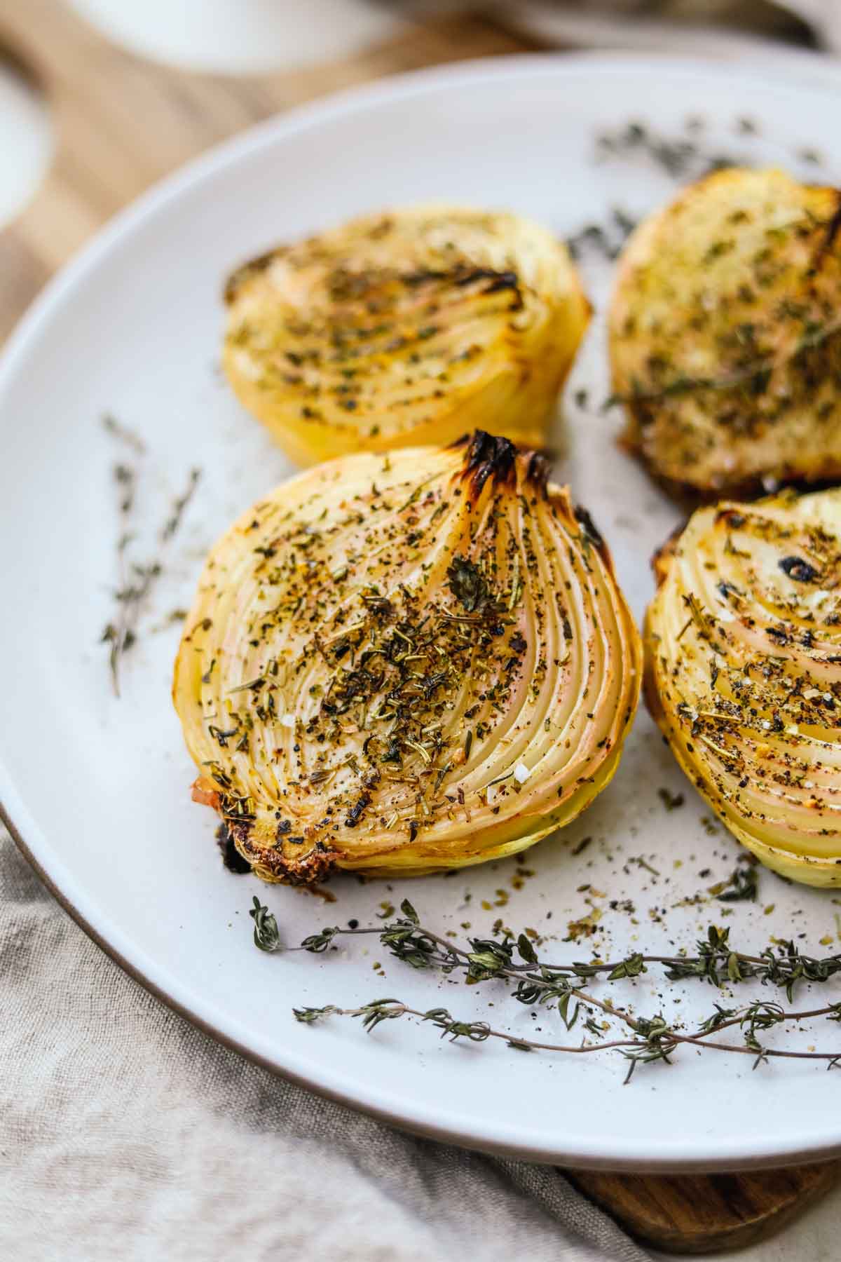Oven roasted onions with herbs baked and served on a Heath Ceramics platter.