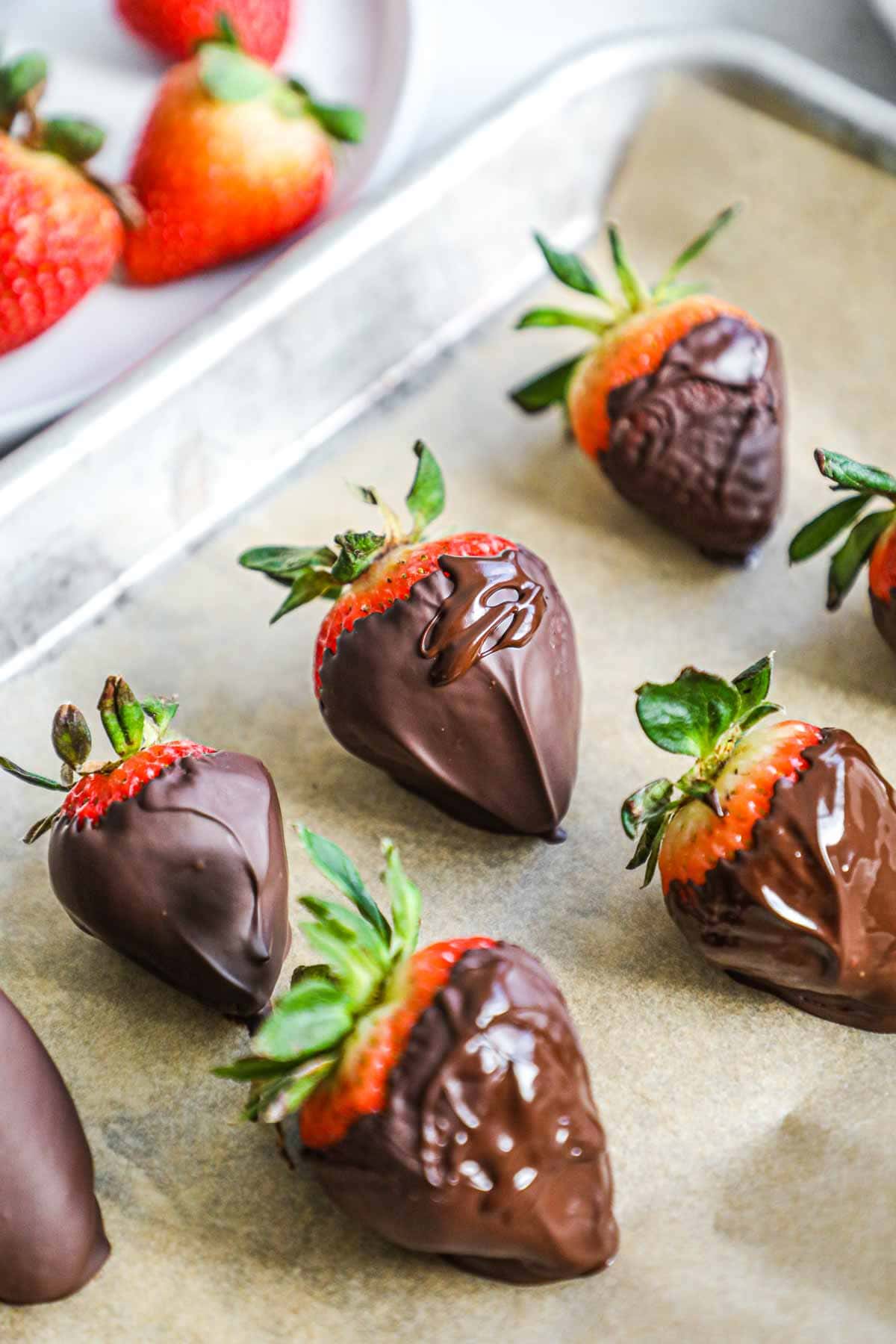 Chocolate covered strawberries on a baking sheet lined with parchment paper.