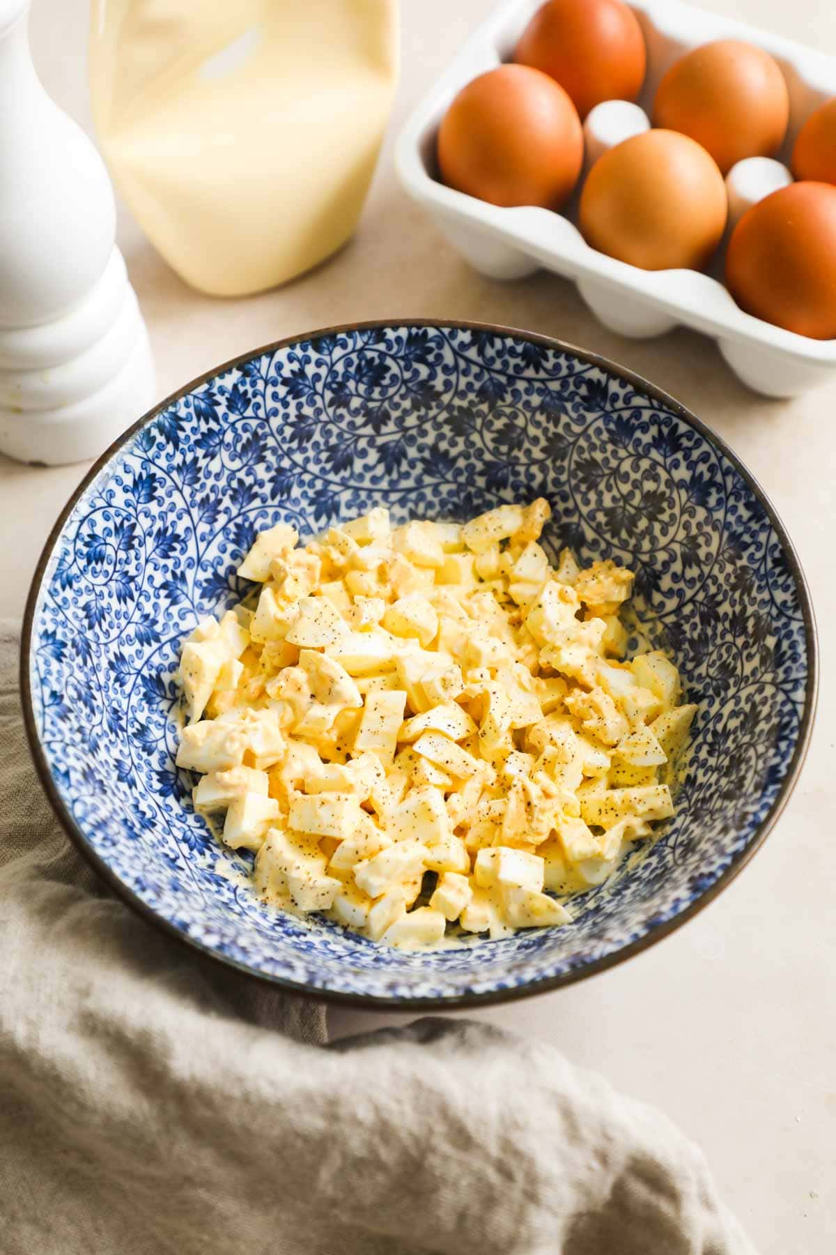 Easy and simple classic egg salad made with Kewpie mayo, salt, pepper, and chopped hard-boiled eggs in a bowl.