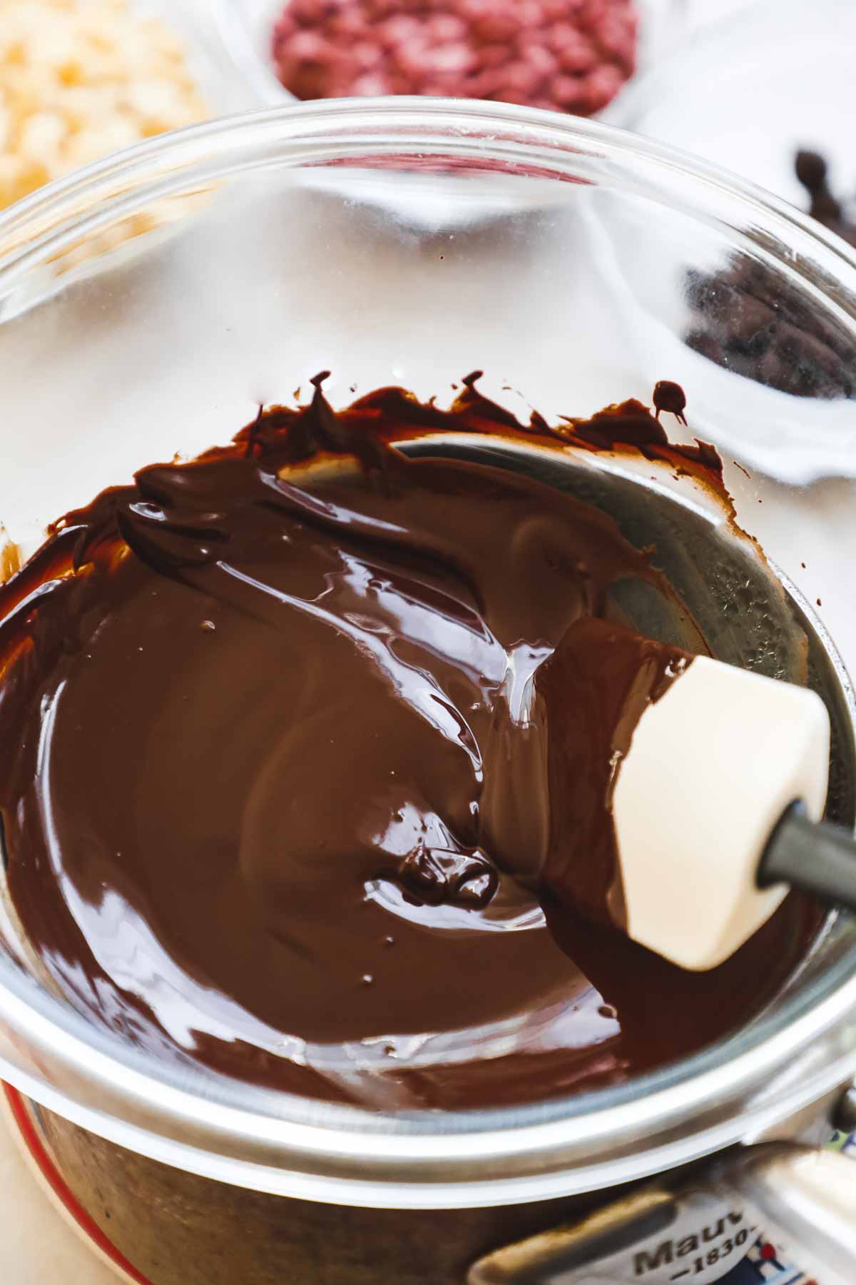 Tempered chocolate in a glass bowl on a double boiler, using the seeding method.